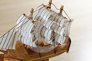 Isolated close-up of a souvenir wooden ship on a light wooden background