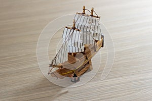 Isolated close-up of a souvenir wooden ship on a light wooden background