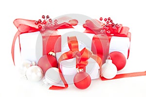 Isolated closeup shot of white Christmas gift boxes with red bows next to Christmas tree ornaments