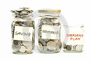 Isolated coins in jar with saving, retirement and emergency plan label