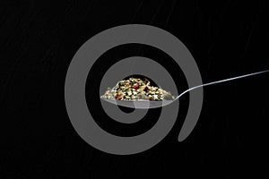 Isolated composition of spoons full of mixed seasonings in a black background