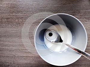 Isolated corn flake in a grey bowl with a spoon viewed from the top