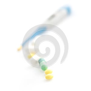 Isolated Digital Thermometer with pills on white background