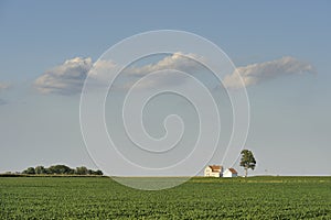Isolated farm house under three clouds