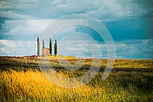 Isolated farmhouse among four cypresses on a hill in Tuscany while a storm is coming photo