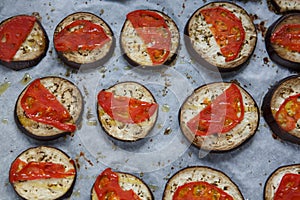 Isolated filled frame close up shot of baked sliced aubergine eggplant with thin tomato slices on top, sprinkled with dry green