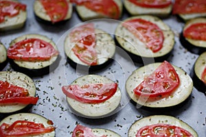 Isolated filled frame close up shot of uncooked raw sliced aubergine eggplant with thin tomato slices on top sprinkled with dry