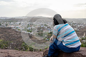 isolated girl sitting at mountain top at evening