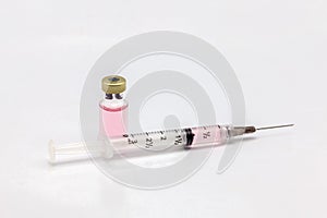 Isolated glass vaccine bottle with colored liquid and a full of colored liquid syringe