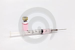 Isolated glass vaccine bottle with colored liquid and a full of colored liquid syringe