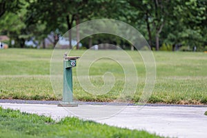 Isolated green drinking water water fountain on a pathway in an empty park