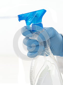 Isolated hand wearing cleaning glove holding a spray bottle