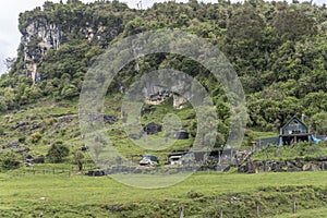 Isolated house on slope under green cliffs, near Inangahua, West Coast, New Zealand