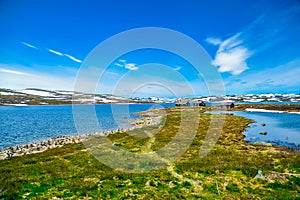 Isolated houses surrounded by beautiful landscape of hills and mountain covered partially with white snow, Norway