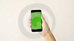 Isolated human hand holding black mobile smart phone device mockup green screen