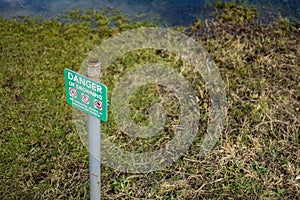 Isolated image of a Danger Sign seen positioned near a deep, open river and adjacent quick sands.