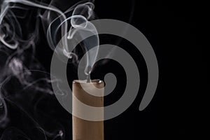 Isolated image of a lit cigarette with a thin wisp of smoke curling from the top