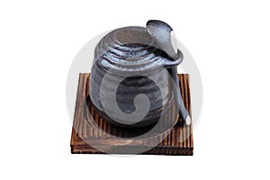 Isolated Japanese custard pudding torched caramel on top served in black ceramic cup on wooden plate with lid and spoon