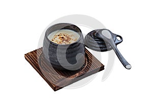 Isolated Japanese custard pudding torched caramel on top served in black ceramic cup on wooden plate with lid and spoon