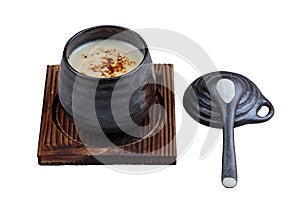 Isolated Japanese custard pudding torched caramel on top served in black ceramic cup on wooden plate with lid and spoon
