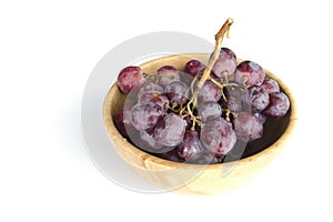 Isolated juicy clusters of large red grapes in a wooden bowl