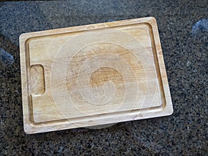 Isolated large wooden cutting board on a granite kitchen