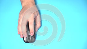 Isolated on a Light Blue Background. Male Hand Holds Wireless Computer Mouse on the Table. Click and Move