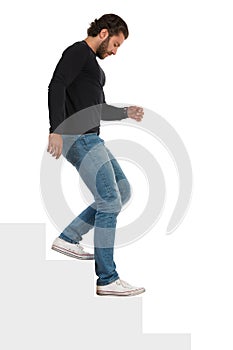 Isolated Man In Black Jersey, Jeans And Sneakers Is Going Down The Stairs. Side View