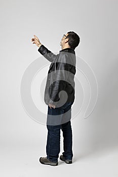 Isolated man on white background is standing with his back turned and pointing to an indefinite point above with his finger