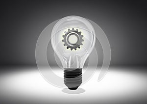 Isolated object shot of a light bulb with cog wheel gear inside on a dark background