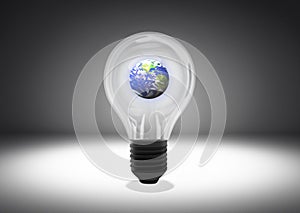 Isolated object shot of a light bulb with the planet Earth inside on a dark background