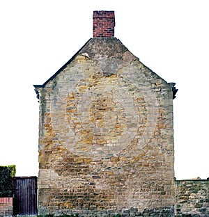 Isolated old yellow and brown sandstone wall of house made of blocks of irregular shape, chimney made of red brick, sandstone fe