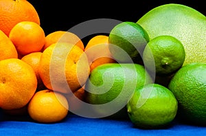 Isolated orange and green color groups citruses fruits on black background. Oranges, tangerines, limes, pummelo, grapefruits on
