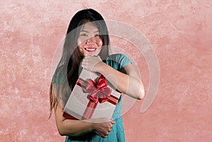 Isolated pink background portrait of young happy and beautiful Asian Chinese woman holding gift box receiving birthday or Christ