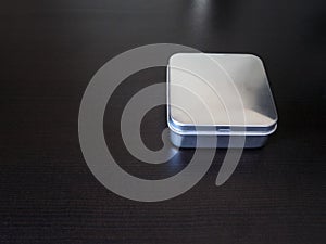 Isolated Plain rectangular tin canister on a dark background holding unknown contents version 2