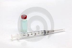 Isolated plastic vaccine bottle with colored liquid and an empty syringe