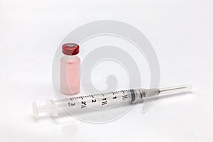 Isolated plastic vaccine bottle with colored liquid and an empty syringe