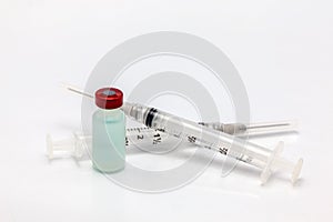 Isolated plastic vaccine bottle with colored liquid and an empty two syringes