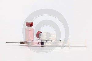 Isolated plastic vaccine bottle one empty lying down with colored liquid and a full of colored liquid syringe