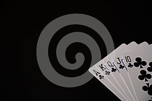 Isolated playing cards with royal flush of clubs poker combination on the black background. Copy space