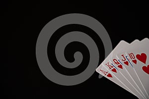 Isolated playing cards with royal flush of hearts poker combination on the black background. Copy space