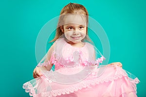 Baby girl in beautiful pink dress on blue isolated