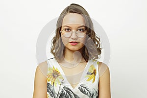 Isolated portrait of cute woman with short hair under shoulders, wearing round spectacles, has a serious and calm
