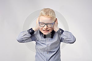 Isolated portrait of gaucasian boy covering ears with hands.