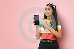 Isolated Portrait of a smiling cheerful young indian asian girl holding blank smartphone screen and showing thumb up with copy