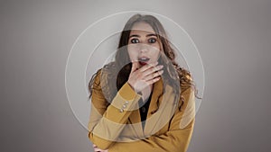 Isolated portrait of woman shocked by some news who is closing her mouth by hand in slowmo