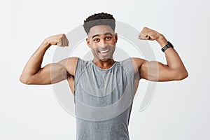 Isolated portrait of young cheerful attractive athletic dark-skinned man with afro hairstyle in sporty grey shirt