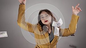Isolated portrait of young cheerful woman who is throwing money in the air in slowmo
