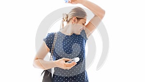 Isolated portrait of young woman smelling her armpits after applying deodorant