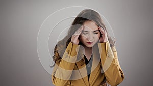 Isolated portrait of young woman suffering from head ache and touching temples by fingers in slowmo